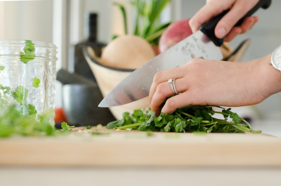 A Woman dices some greens with a large knife